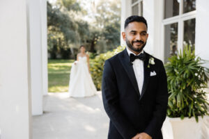 Classic Timeless Groom Wearing Black Tuxedo and Bow Tie Waiting for Bride First Look Portrait