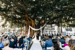 Nature Inspired Banyan Tree Outdoor Wedding Ceremony Altar Ideas | White Drapery with Wooden Cross | Tampa Bay Wedding Planner Wilder Mind Events | Tampa Bay Videographer J&S Media | Downtown St. Pete Venue N. Straub Park