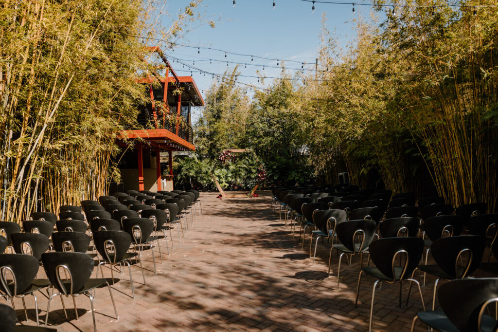 Outdoor Bamboo Garden Wedding Ceremony With Hexagon Geometric Arch and Market Lights | Modern Black Chair Inspiration | Tampa Bay Wedding Venue NOVA 535