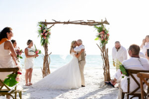 First Kiss Beach Wedding Ceremony Driftwood Beach Wedding Ceremony Arch | Tropical Flower Arrangements Ideas | Tampa Bay Florist Save The Date Florida