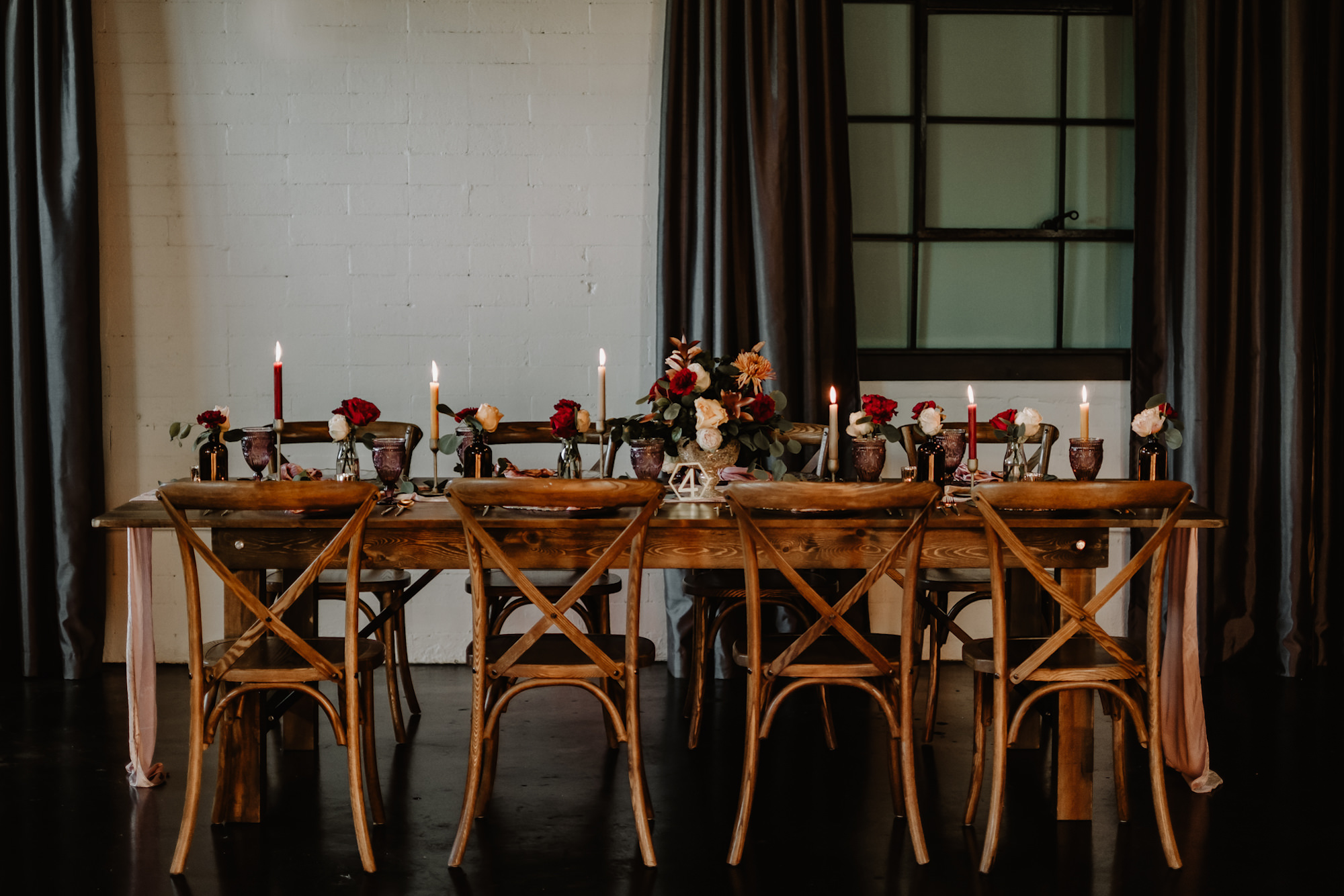 Moody Fall Wedding Reception Ideas | Cross Back Wooden Table Wedding Reception Chairs | Red Burgundy Taper Candles and Low Rose Centerpiece Table Decor Ideas