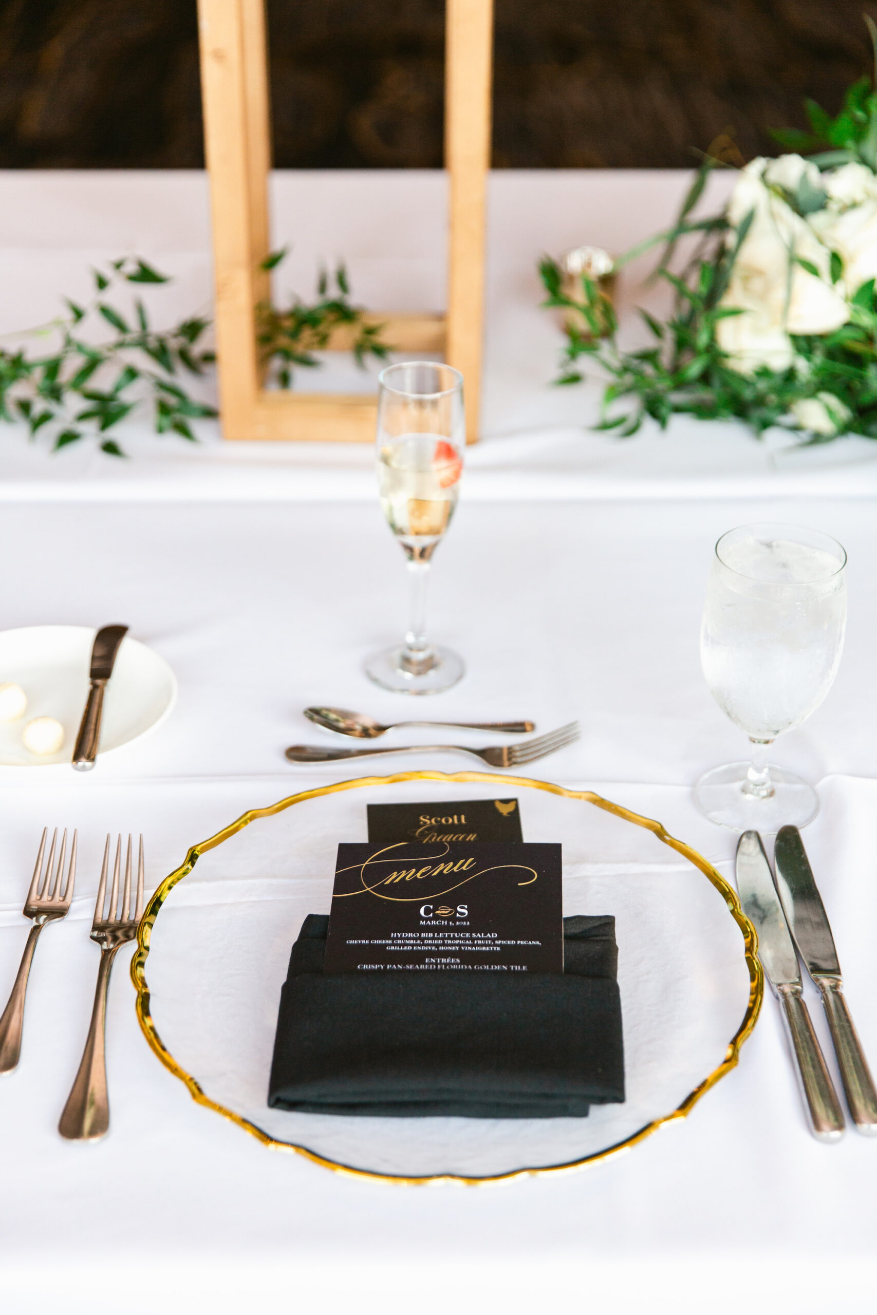 Classic Black White and Gold Wedding Reception Decor Inspiration Table Setting with Black Linen, Gold Rim Chargers, White Tablecloth | Tampa Bay Decor Kate Ryan Event Rentals