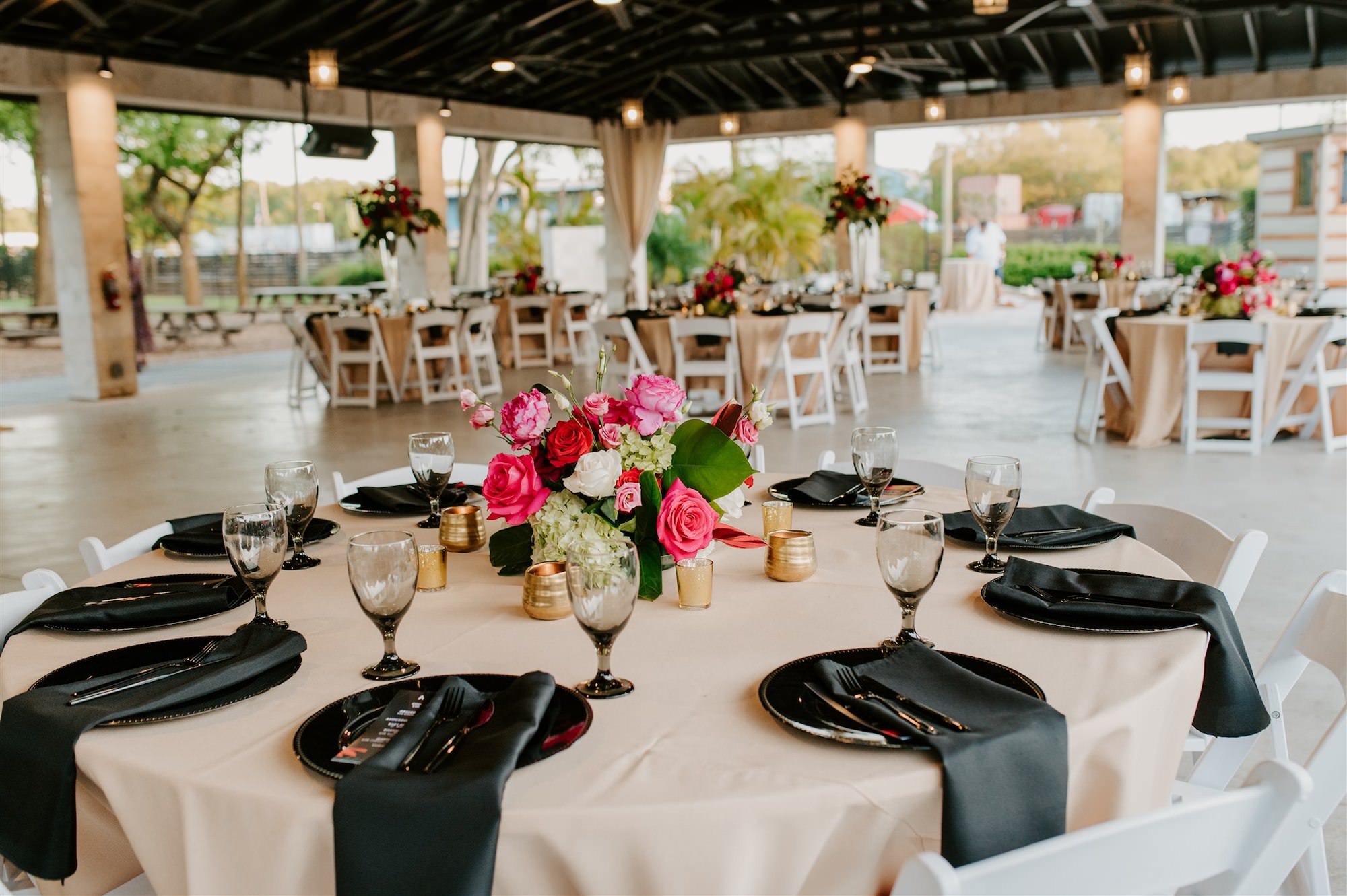Modern Tropical Wedding Reception Decor Inspiration | Black Chargers, Napkins, and Glassware with Pink Fuchsia Rose and Hydrangea Centerpieces and Champagne Linens | Tampa Bay Rentals Gabro Event Services