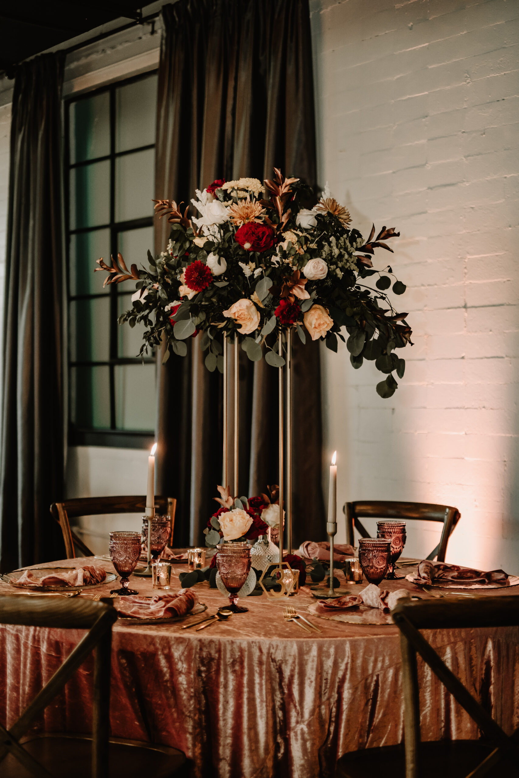 Tall Gold Metal Vase Centerpieces with Dark and Mood Fall Inspired Floral Arrangements with Dusty Rose Linens and Vintage Glasses | Fall Wedding Reception Table Ideas