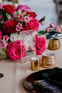 Modern Tropical Wedding Reception Decor Ideas | Black Chargers, Napkins, and Glassware with Pink Fuchsia Rose and Hydrangea Centerpieces and Champagne Linens with Acrylic Gold Table Number | Tampa Bay Rentals Gabro Event Services