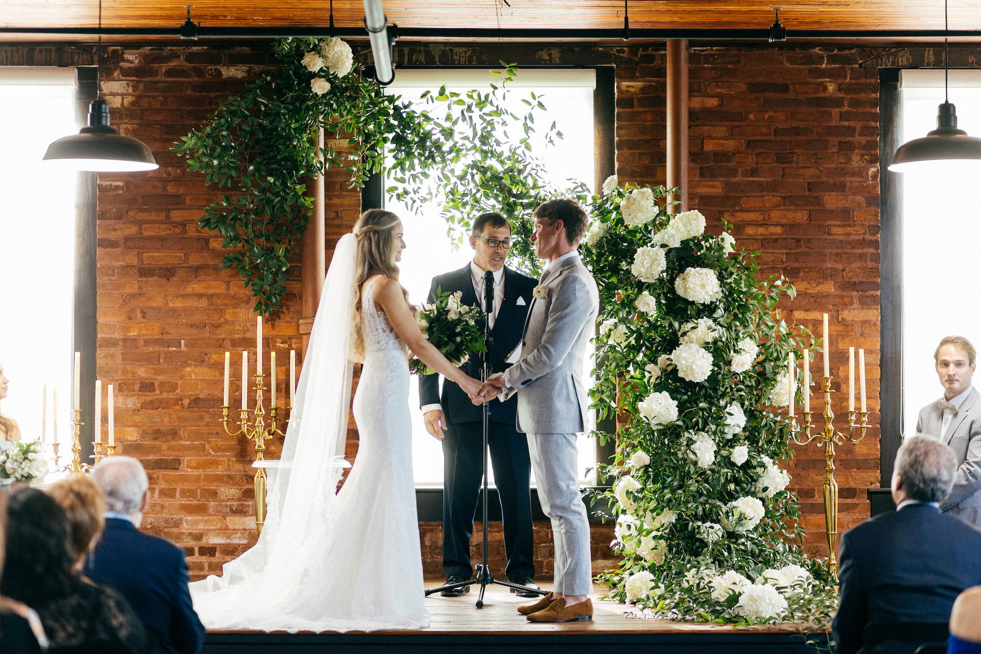 Bride and Groom Wedding Vows, Greenery Ceremony Arch with White Flowers| Tampa Bay Wedding Venue J.C. Newman Cigar Co. | Planner Parties A La Carte | Florist Bruce Wayne Florals