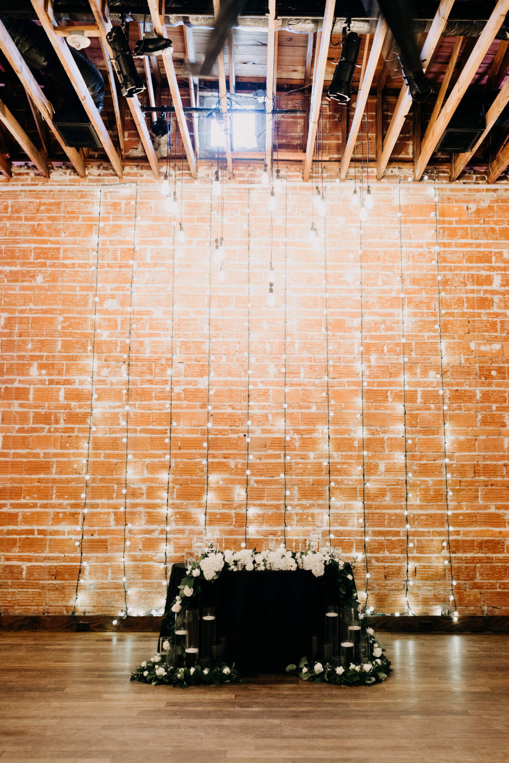 Simple Classic Black and White Wedding Reception Decor, Sweetheart Table with Red Brick Wall Backdrop and Hanging Lights | Tampa Bay Wedding Photographer Amber McWhorter Photography | Unique Industrial Wedding Venue NOVA 535