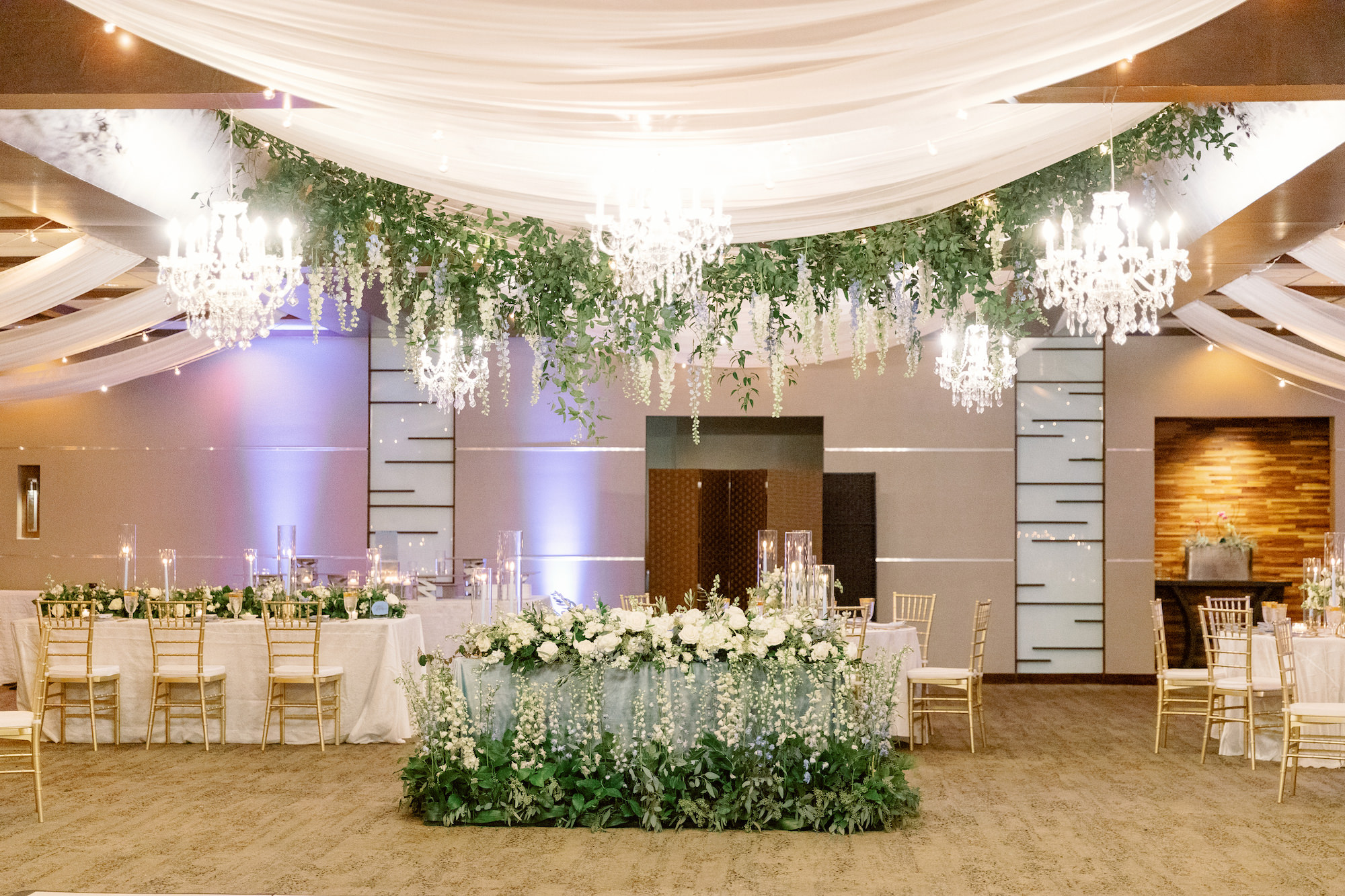 Reception Decor Ideas | Romantic Indoor White and Gold Spring Wedding Reception with Gold Chiavari Chairs and White Ceiling Drapery with Hanging Floral Arrangements and Garden Inspired Sweetheart Table | Sarasota Wedding Planner MDP Events | Florist Botanica International Design Studio | Venue Marie Selby Gardens