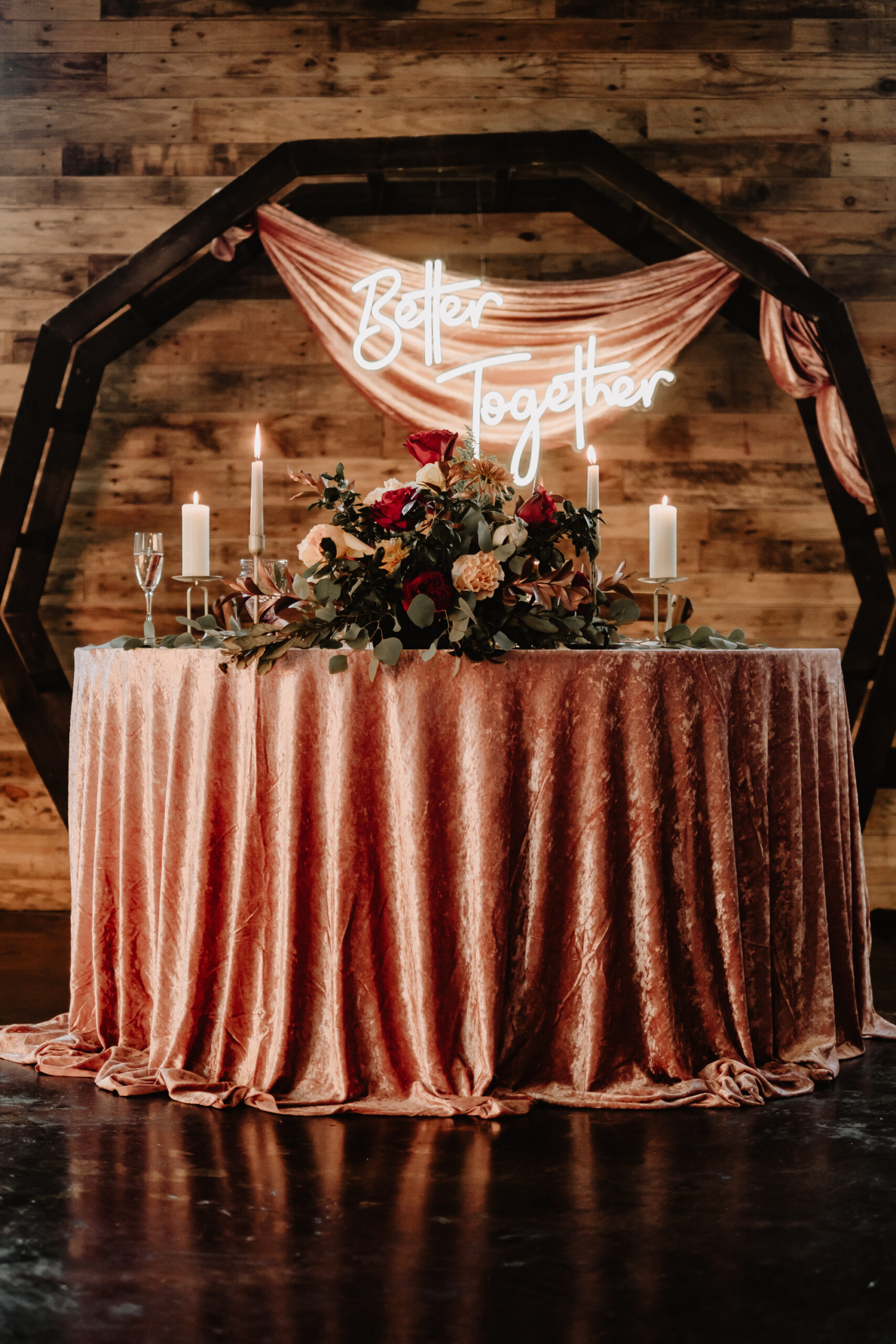 Sweetheart Head Wedding Reception Table With Dusty Rose Velvet Linens | Fall Inspired Maroon, Burgundy Cream, and Greenery Table Floral Arrangement, Neon Sign and Geometric Arch | Moody Fall Wedding Reception Ideas