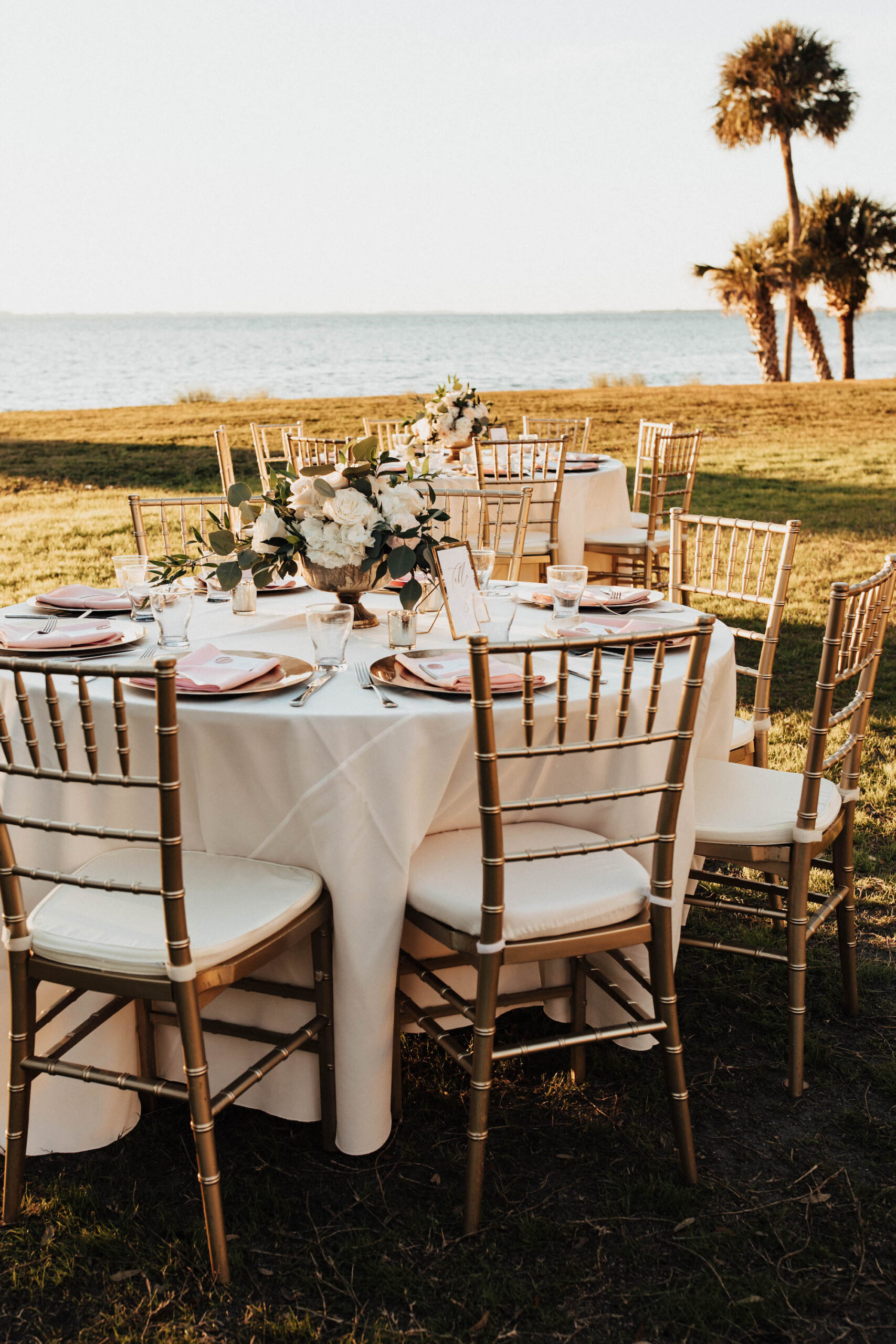 Gold Chiavari Chairs with White Linen Tables and Floral Centerpieces | Romantic Waterfront Outdoor Garden Wedding Reception