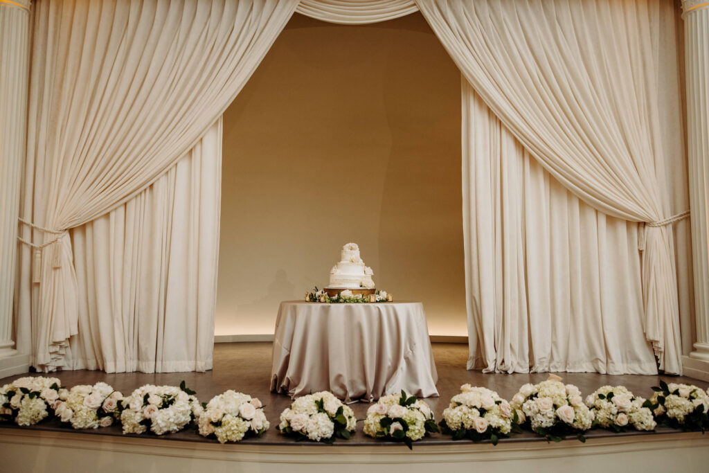 Luxurious Wedding Cake Table on Stage | Cream Satin Linens | Tampa Bay Rentals A Chair Affair