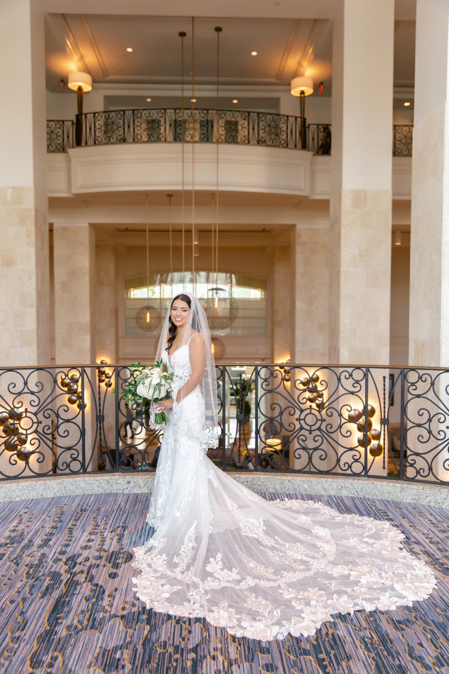Bride inside Tampa Marriott Water Street Holding Greenery and White Floral Bouquet | Adore Bridal Hair and Make Up | Florida Wedding Florist Save The Date