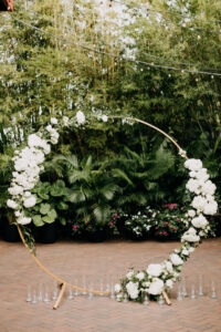 Simple Classic Outdoor Bamboo Courtyard Wedding Decor, Hanging Bistro Lights, Round Circular Gold Metal Arch with Lush White and Greenery Flowers | St. Pete Wedding Florist Save the Date Florist | Wedding Venue NOVA 535