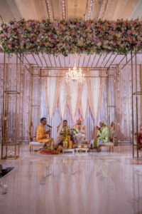 Traditional Indian Wedding Ceremony, Bride and Groom Under Mandap Altar Decorated with Luxurious Florals and Chandelier, Rose Gold Draping and Lighting | Florida Wedding Venue Hilton Downtown Tampa