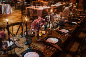 Dark and Moody Tablescape with Pampa Leaf Detailing, Mauve Florals, Black Chargers, White Plates on Wooden Tables Reception Ideas