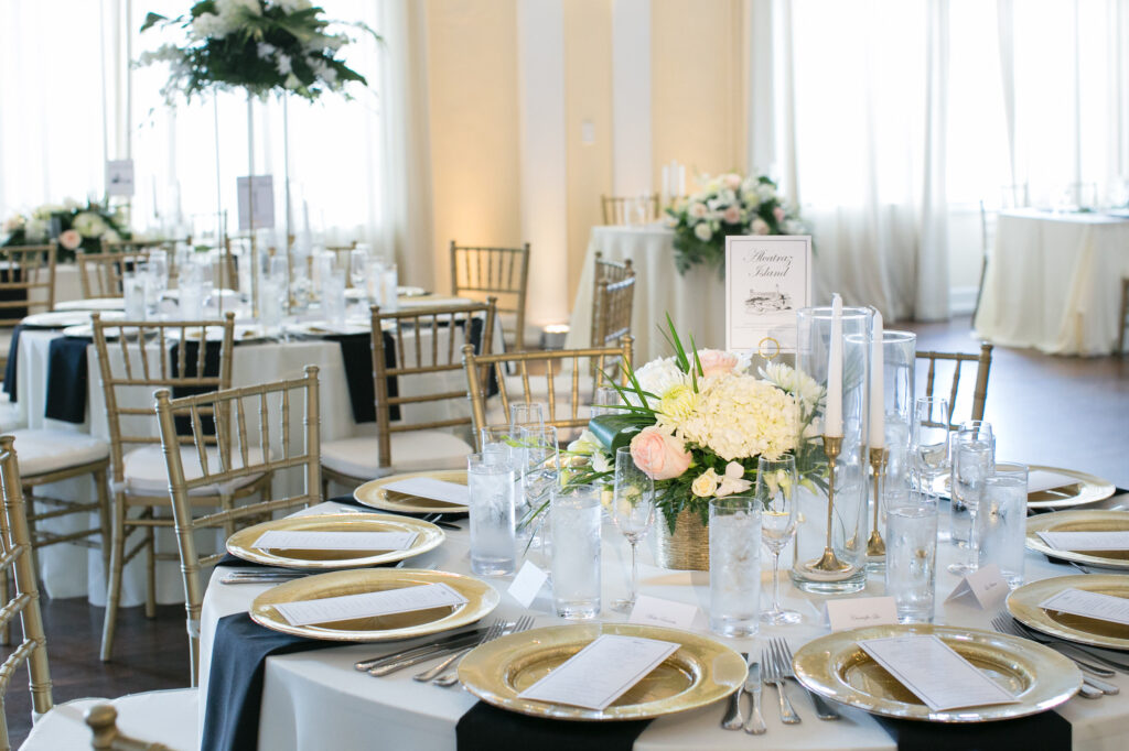 Elegant White Hydrangeas, Blush Roses, Chrysanthemums, and Greenery Tropical Centerpiece Inspiration | Gold Chiavari Chairs | Ivory and Black Linens with Gold Chargers and Silver Flatware Wedding Reception Table Setting Ideas | Tampa Bay Rentals A Chair Affair