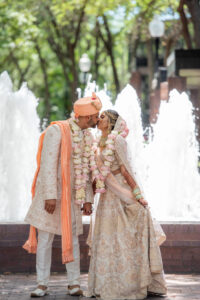Florida Bride and Groom Kissing, Wearing Traditional Indian Wedding Mala, Ivory and Pink rose flower garland, Rose Gold and White Saree, Coral Peach Turban | Tampa Bay Wedding Venue Hilton Downtown Tampa