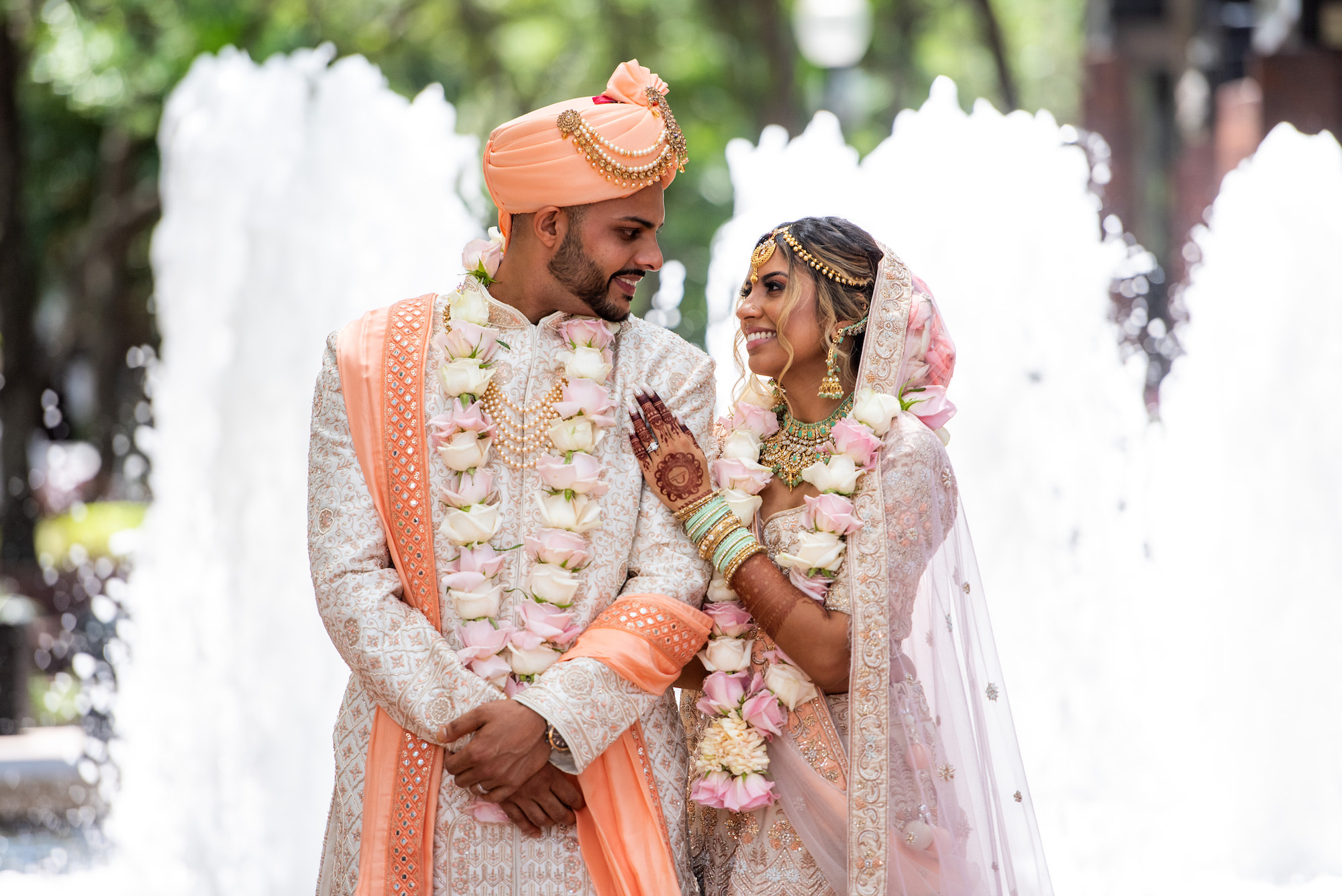 Florida Bride and Groom Kissing, Wearing Traditional Indian Wedding Mala, Ivory and Pink rose flower garland, Rose Gold and White Saree, Coral Peach Turban | Tampa Bay Wedding Venue Hilton Downtown Tampa | Michele Renee the Studio