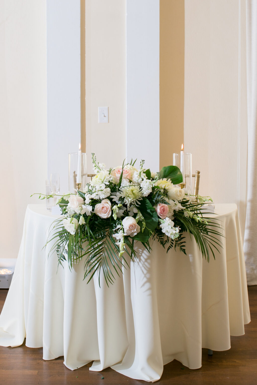 Elegant Palm Leaf, Fern, Pink Roses, Chrysanthemums, and Snapdragon Tabletop Flower Arrangement for Sweetheart Table Ideas | Tropical Wedding Reception Decor Inspiration