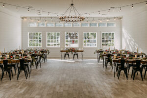Moody Modern Rustic Wedding Reception Inspiration Market Lights, Wooden Tables and Black Metal Chairs | Sweetheart Table | Tampa Bay Cross Creek Ranch The White Oak Barn