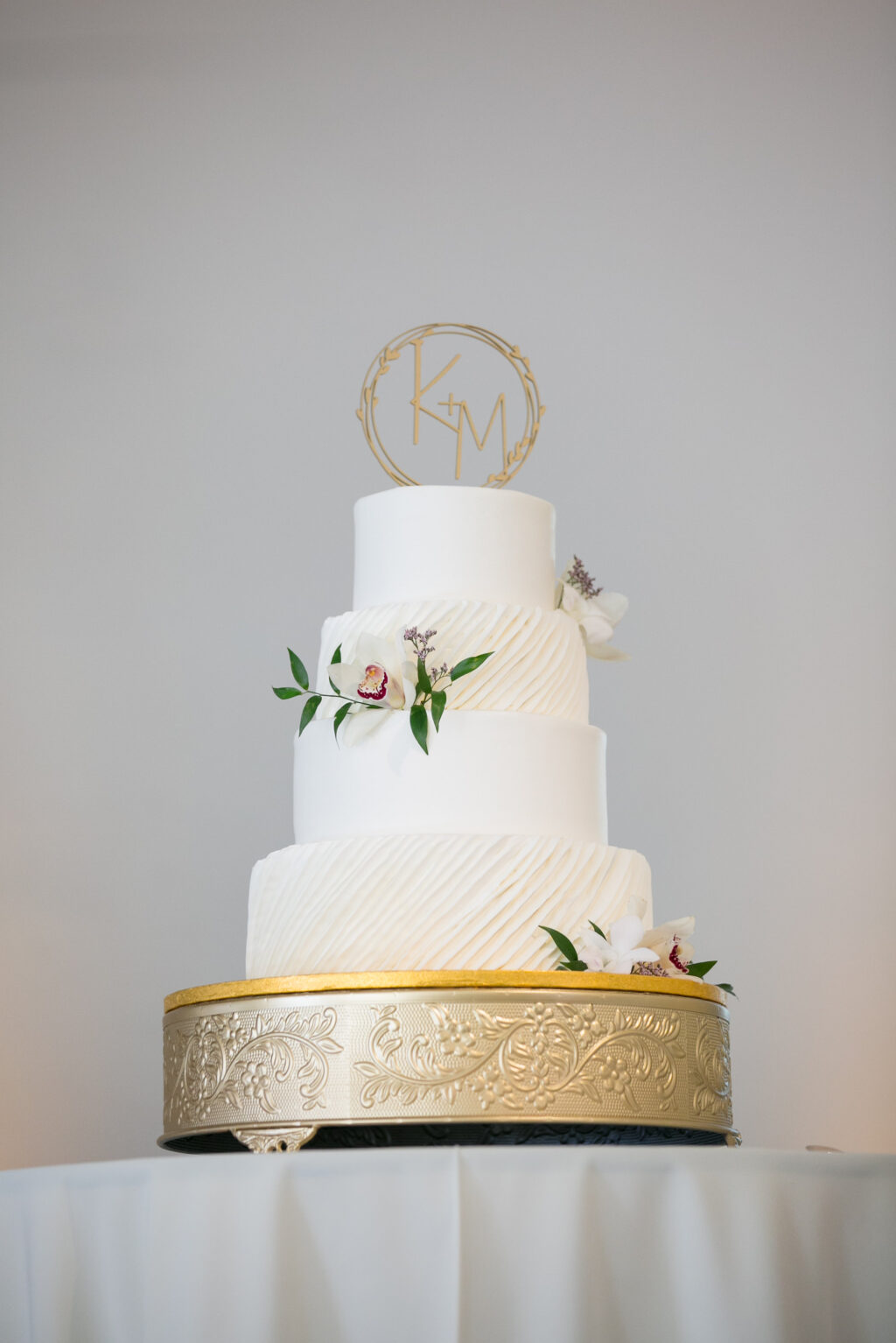 Four-tiered Round Ivory Textured Wedding Cake with Floral Accents and Custom Laser-cut Cake Topper
