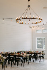 Moody Modern Rustic Wedding Reception Inspiration with Large Ring Chandelier, Market Lights, Wooden Tables and Black Metal Chairs | Sweetheart Table | Tampa Bay Cross Creek Ranch The White Oak Barn