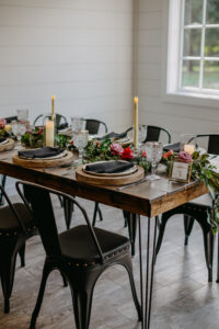Hairpin Leg Wood Wedding Reception Dining Tables with Wooden Chargers, Black Napkins, Rose and Greenery Floral Centerpieces | Moody Modern Rustic Wedding Reception Ideas | Tampa Bay Wedding Florist Monarch Events and Design