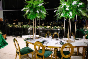 Modern Glamorous Gold Serpentine Table with Modern Gold Louis Pop Chairs | Tall Gold Flower Stands with White Stock Flowers, Palm Leaves, and Monstera Greenery Inspiration | Tampa Bay Florist FH Events | Rentals A Chair Affair