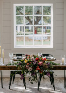 Wedding Reception Sweetheart Head Table with Table Top Red, Purple, Maroon, and greenery Floral Arrangement | Moody Modern Rustic Wedding Decor Ideas | Tampa Bay Florist Monarch Events and Design