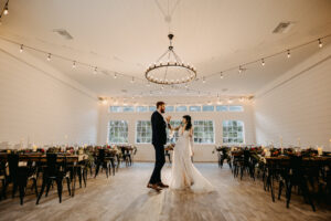 Moody Modern Rustic Wedding Reception Inspiration Market Lights, Wooden Tables and Black Metal Chairs | Sweetheart Table | Tampa Bay Cross Creek Ranch The White Oak Barn