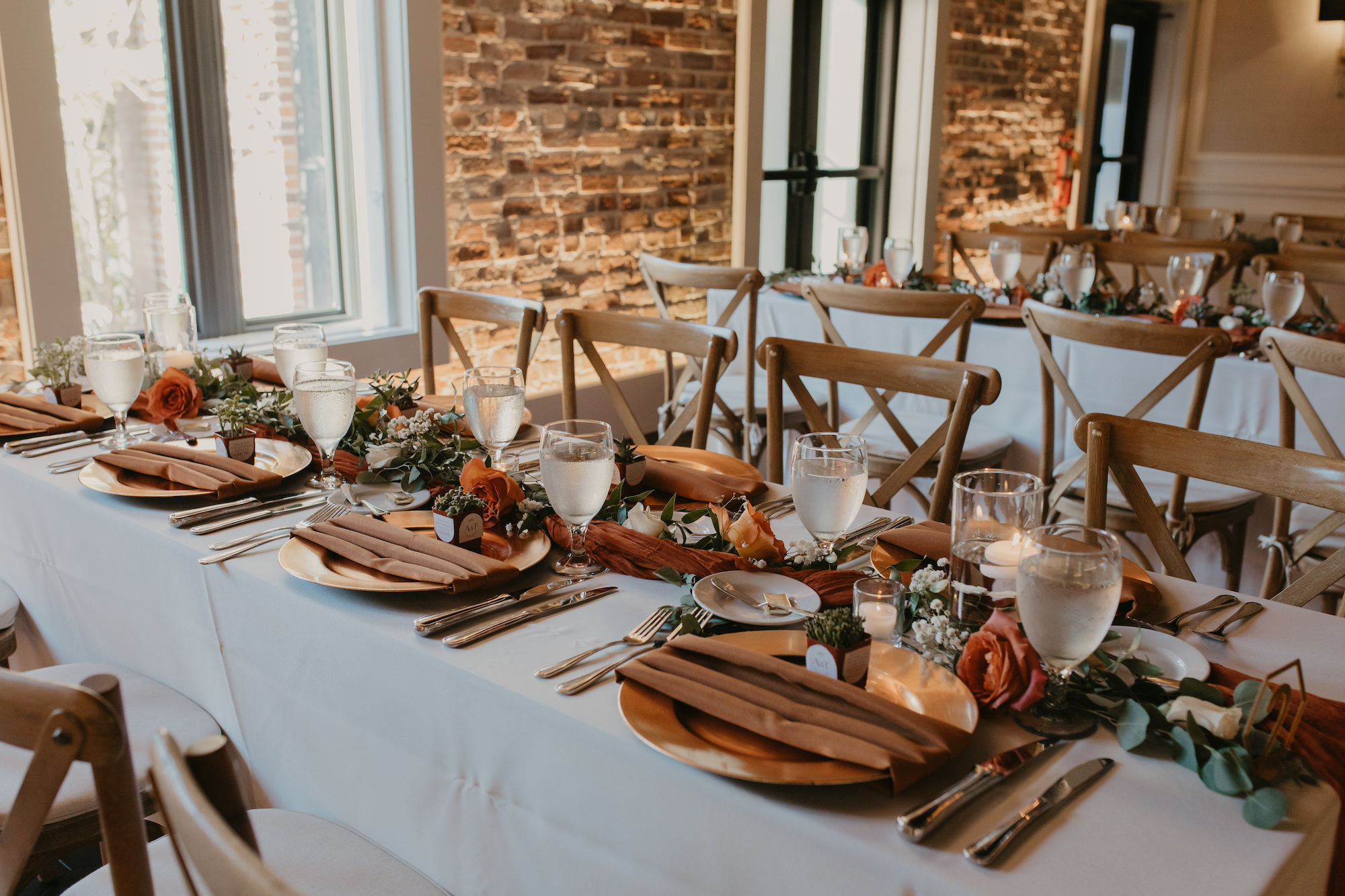 Wedding Guest Succulent Gift Ideas | Boho Reception Table Setting Inspiration | Eucalyptus Garland with Terracotta Roses and Baby's Breath Centerpiece Ideas | Gold Chargers and Flatware | Wooden Crossback Chairs