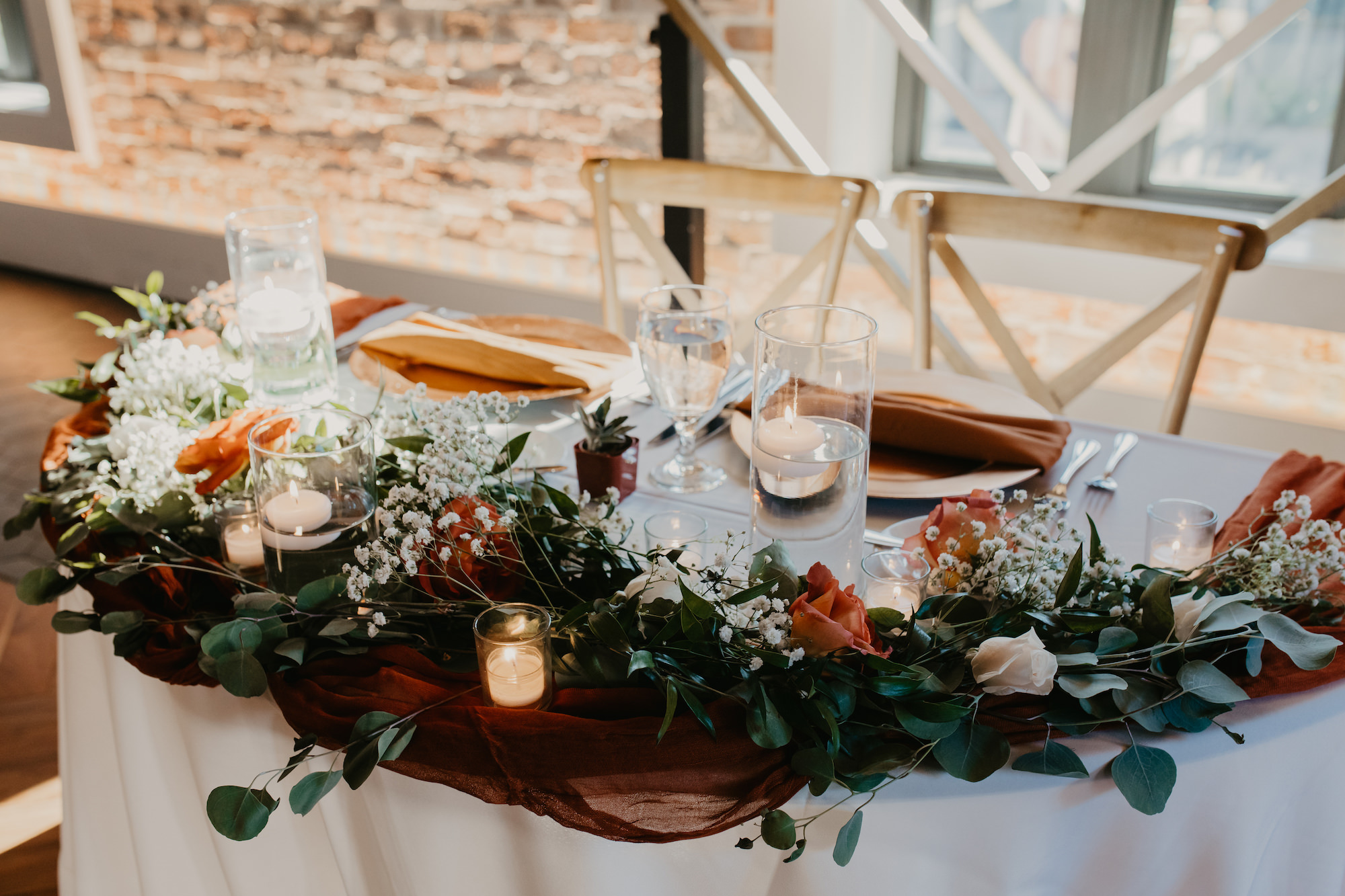 Half Circle Sweetheart Table Decor Ideas | Crossback Wooden Chairs with Terracotta Cheese Cloth, Floating Candles | Eucalyptus Garland with Roses and Baby's Breath