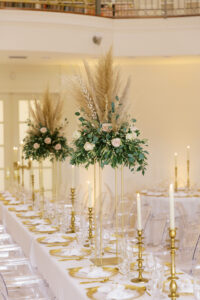Vintage Old Hollywood Gatsby Inspired Wedding Reception Decor, Long Head Feasting Table, White Linens, Gold Chargers, Tall Floral Boho Centerpieces with greenery, blush pink roses and pampas grass, Gold Candlesticks | Tampa Bay Wedding Venue The Whitehurst Gallery | Rentals Gabro Event Services