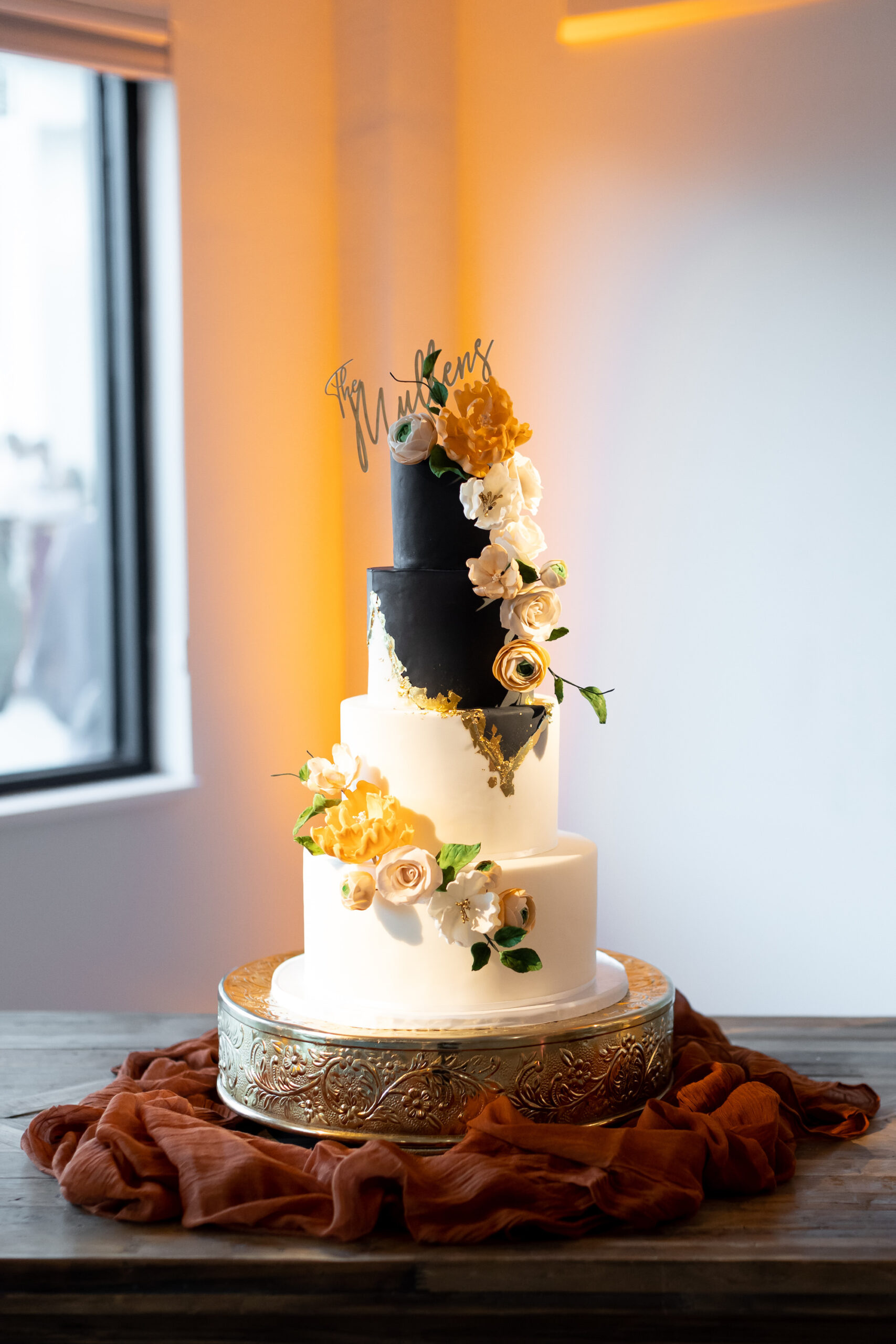 Modern Four-Tiered Black, White, and Gold Wedding Cake On a Gold Cake Stand | Tampa Bay Wedding Cake Tampa Bay Cake Company