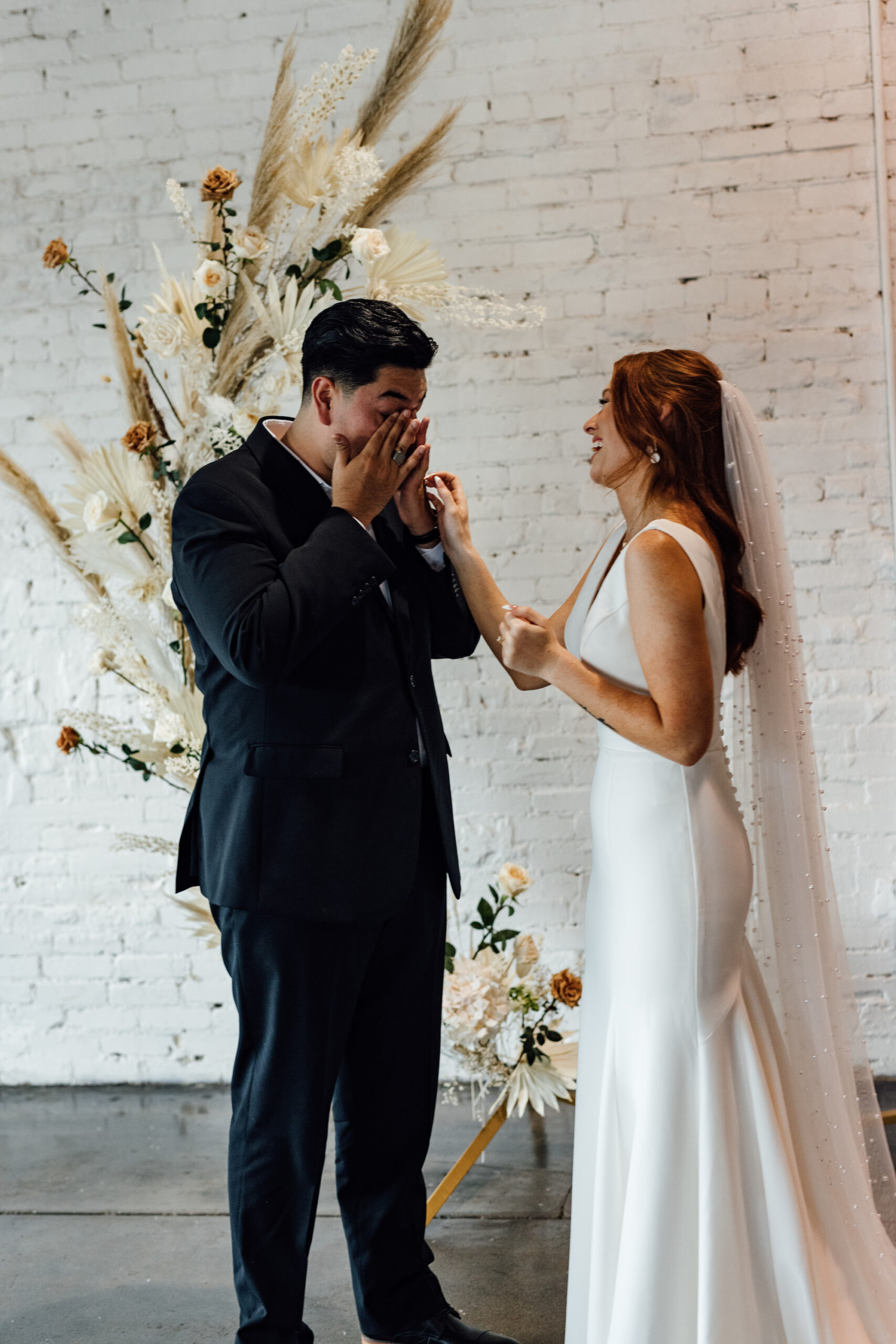 Emotional Bride and Groom First Look Wedding Portrait | Indoor Wedding Ceremony | Asymmetrical Round Boho Arch with Boho Pampas Grass White Palm Frond Floral Arrangements | Tampa Bay Wedding Venue Haus 820