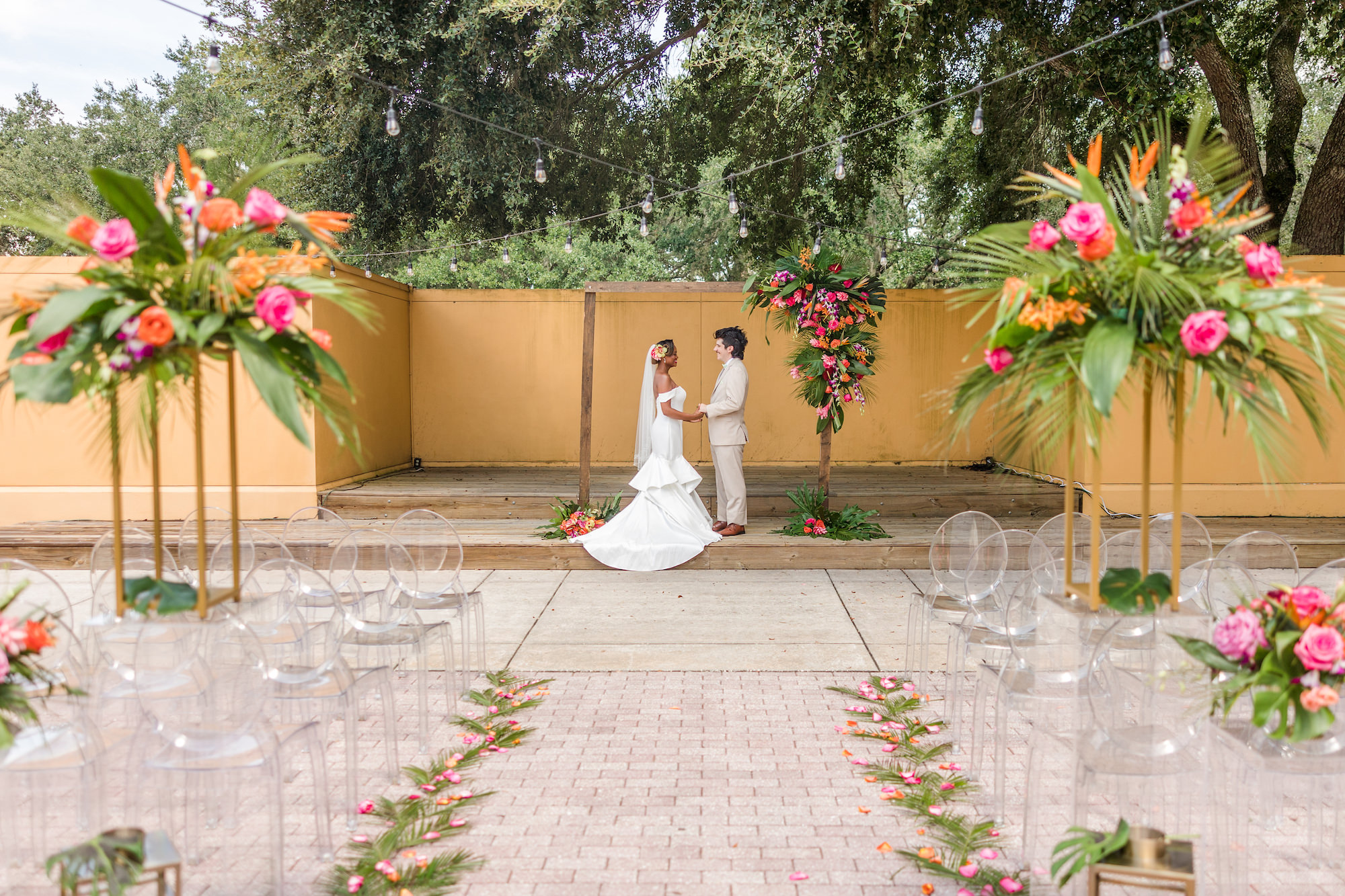 Pink and Orange Tropical Outdoor Courtyard Wedding Ceremony | Acrylic Oval Ghost Chairs | Tampa Bay Rental A Chair Affair | Wedding Venue Tampa Palms Golf & Country Club | Wedding Planner Kelci Leigh Events | Florist Save the Date Florida