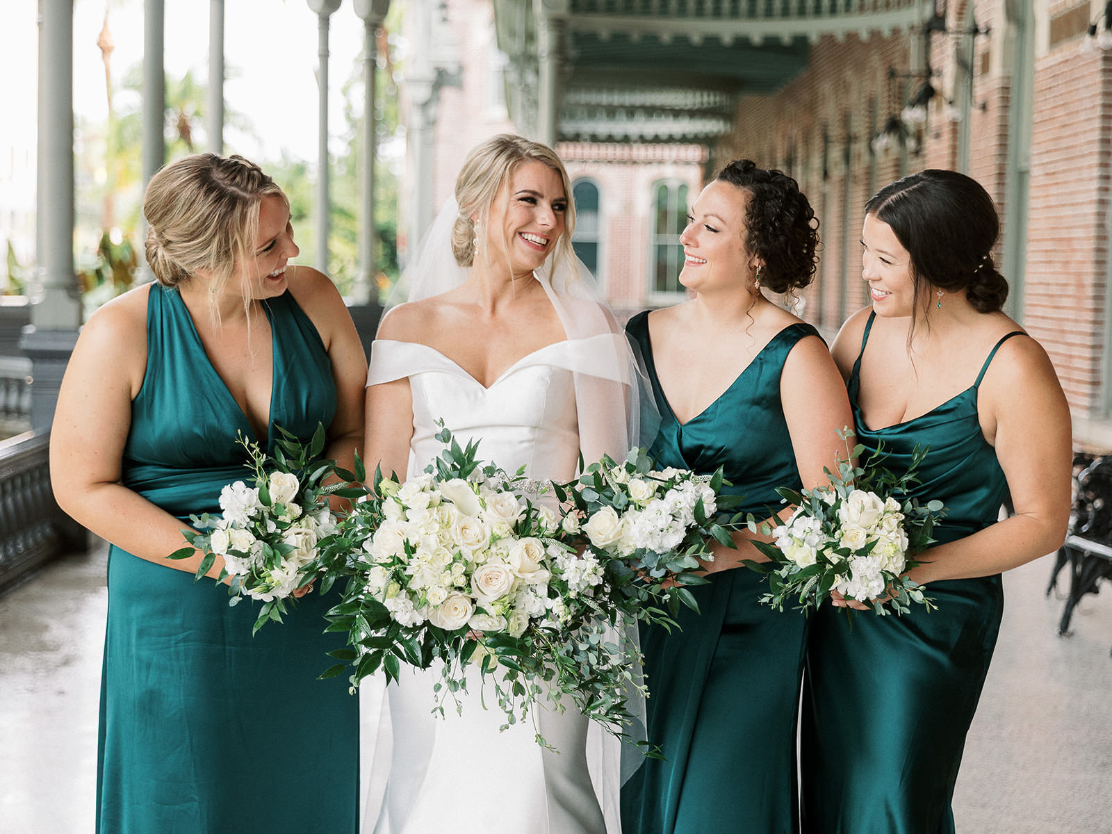 White Rose and Ruscus Greenery Bridal Bouquet | Elegant White Ivory Satin Off the Shoulder Fit and Flare Maggie Sottero Wedding Dress | Mismatched Emerald Green Satin Bridesmaid Dress Ideas | Tampa Bay Henry B. Plant Museum Photo Inspiration