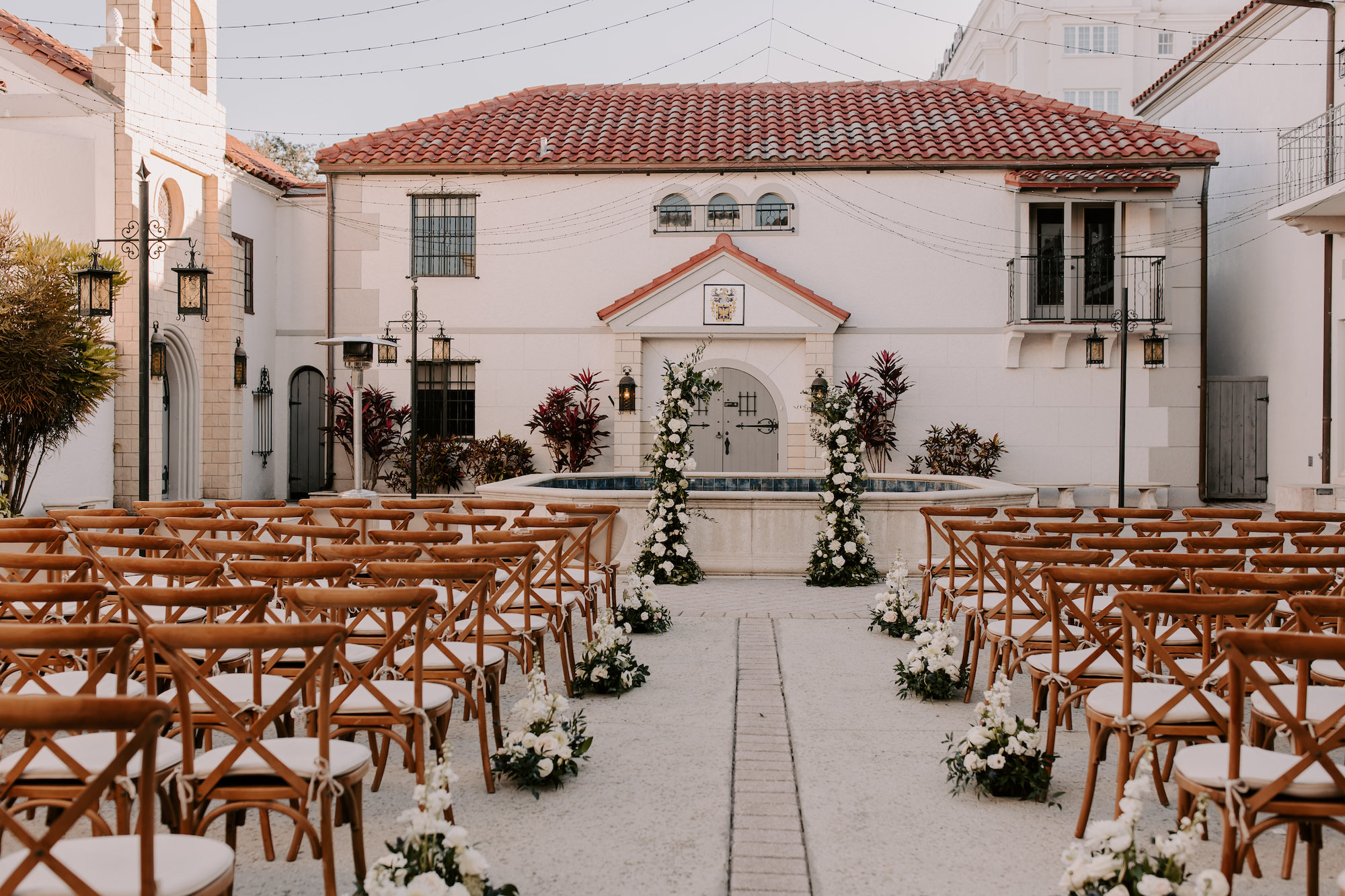 Romantic Spanish Inspired Outdoor Wedding Venue | Wooden Crossback Chair | Asymmetrical Floral Column Wedding Arch | Sarasota Bishop Museum