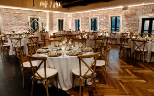 Modern Exposed Brick Indoor Wedding Reception | Wooden Crossback Chairs | Candlelit Centerpieces | St Petersburg Venue Red Mesa Events