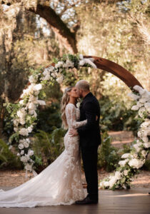 Bride and Groom Reading Wedding Vows with Circular Wooden Arch and White Flowers | Tampa Bay Wedding Venue Cross Creek Ranch
