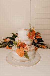 Semi-Baked Three-Tiered Round Wedding Cake with Fern, Anthurium, Pin Cushion Protea, and Garden Rose Accents | Tropical Cake Table Ideas