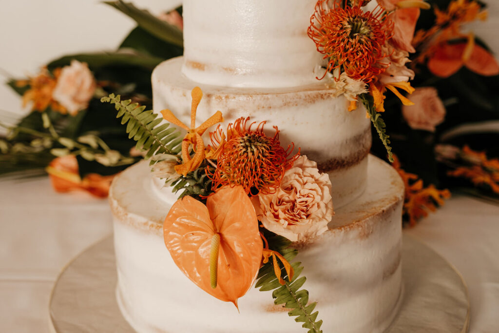 Semi-Baked Three-Tiered Round Wedding Cake with Fern, Anthurium, Pin Cushion Protea, and Garden Rose Accents | Tropical Cake Table Ideas