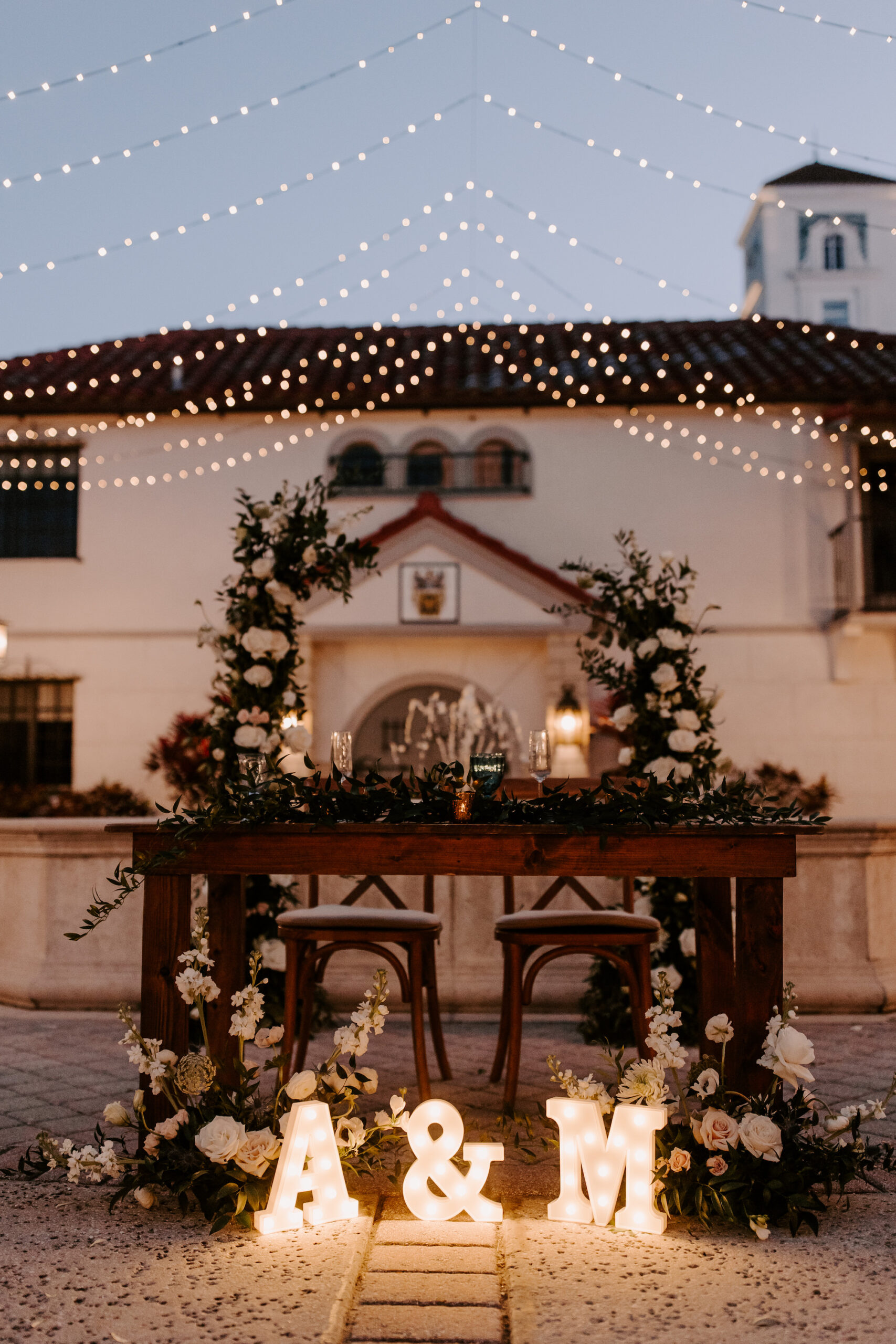 Rustic Sweetheart Head Table Ideas | Outdoor Romantic Wedding Reception Decor | Market Lights | Light Up Marquee Letters | White Rose and Greenery Floral Arrangements
