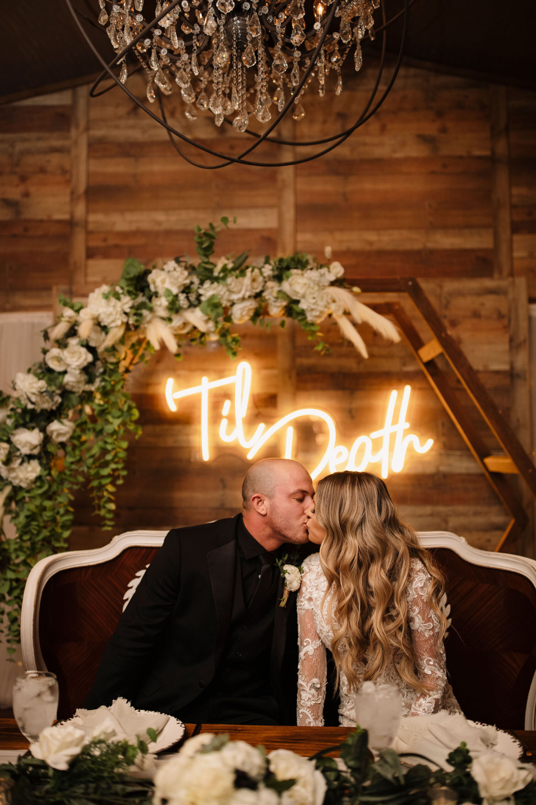 Wedding Reception Sweetheart Table With Hexagon Arch and White Flowers with Greenery and Pampas Grass Decor Ideas | Bench Seating | Personalized Neon Sign Ideas | Tampa Bay Wedding Venue Cross Creek Ranch