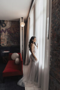 Ivory Spaghetti Strap Sheer Side Lace Mermaid Wedding Dress with Tulle Skirt Ideas | Bride Getting Ready in Modern Hotel Suite | Ybor Wedding Venue Hotel Haya | Hair and Makeup Artist Femme Akoi Beauty Studio
