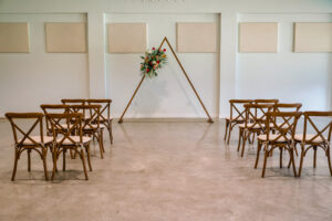 Triangle Wedding Ceremony Arch with Tropical Flower Spray Inspiration | Wooden Crossback Chairs