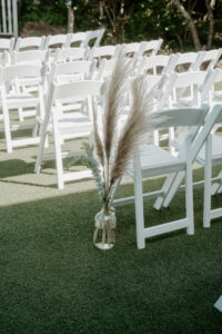 White Folding Wedding Ceremony Chairs with Pampas Grass Wedding Aisle Decor and Glass Vase Inspiration