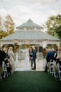 Bride and Groom Exchange Vows Under Outdoor Wedding Ceremony with White Palapa and White Folding Chairs | Florida Florist Beneva Flowers | Truly Forever Bridal