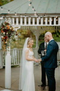 Bride and Groom Exchange Vows Under Outdoor Wedding Ceremony with White Palapa and White Folding Chairs | Florida Florist Beneva Flowers | Truly Forever Bridal