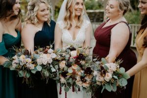 Bride with Bridesmaids in Fall Jewel Toned Bridesmaids Dresses Wedding Portrait with Dark and Moody Fall Bouquet Ideas | Sarasota Wedding Dress Boutique Truly Forever Bridal Tampa | Florist Beneva Weddings